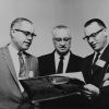 R. C. Spanger, W. B. Ochs, and J. W. Bothe looking at an issue of the Canadian Union Messenger, 1960s