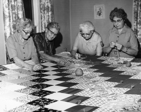 Quilt top number 100 is almost completed by (left to right) Mrs. Gladys Schmidt, Bertha K. Wohlers, Mrs. Ivah Wilson, and Mrs. Elsie Leffler at the Berrien Springs Springs Community Services Center