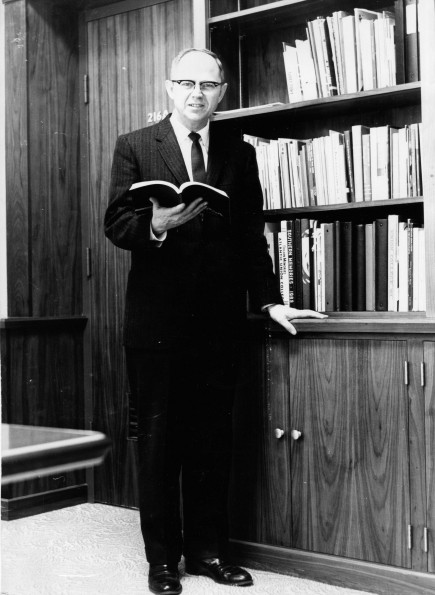 Andrews University president Richard L Hammill holding a book in his office