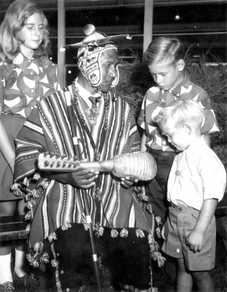 South American native shows his musical instrument to three unknown western missionary children