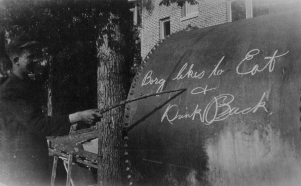 Young man pointing to a sign written on a large tube.