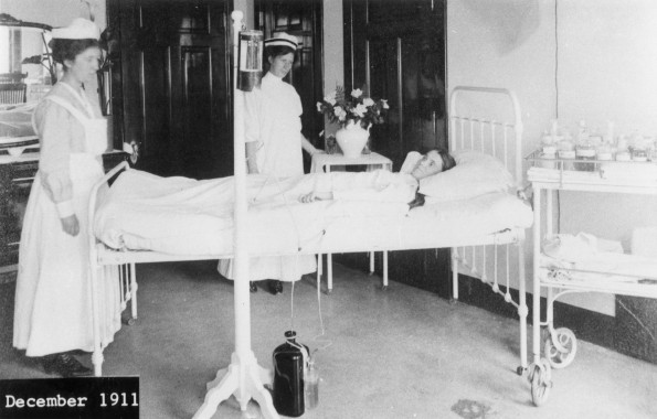 Battle Creek Sanitarium patient room with a patient and two attendants, 1912