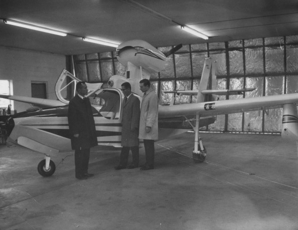 Three man standing in front of a plane at the Andrews University Airport T-hangar