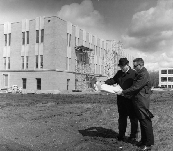 V. E. Garber and Andrews University construction manager, John Kriley, looking at blueprints for the Administration Building under construction in the background