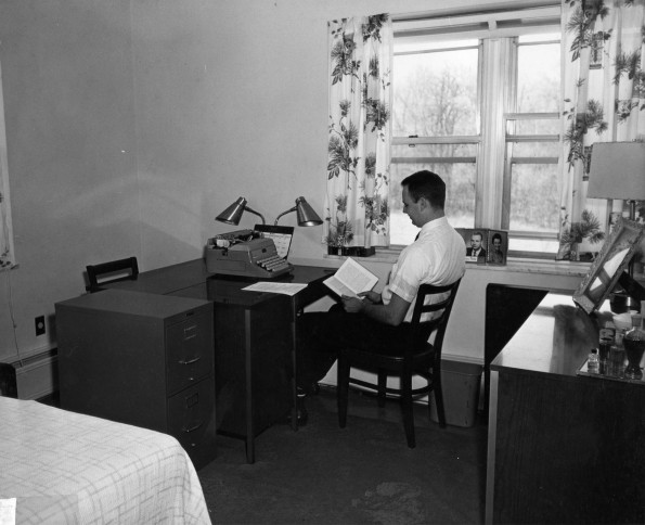 A student reading a book in a bedroom-study area of Andrews University Garland Apartments