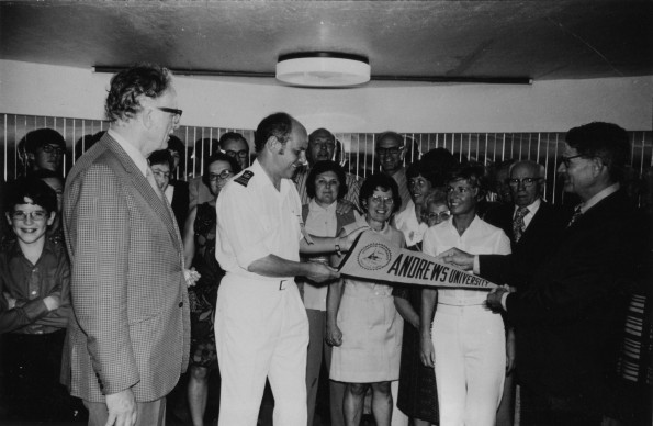 [Horace John Shaw and Wilson L. Trickett presenting an Andrews University banner to the captain of the cruise ship on which Andrews alumni sailed to the south Pacific]