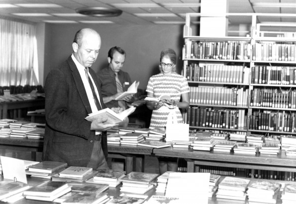 [Richard Powell, Larry Bergstrom, and Donna Stout looking over the book display at the James White Library]