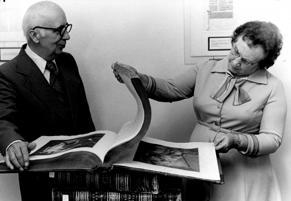 [George Suhrie and Mary Jane Mitchell looking at ancient Bibles that are part of the Suhrie Bible Collection in the Andrews University Heritage Room]