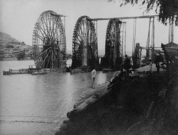 Four large water wheels under construction in a Chinese river