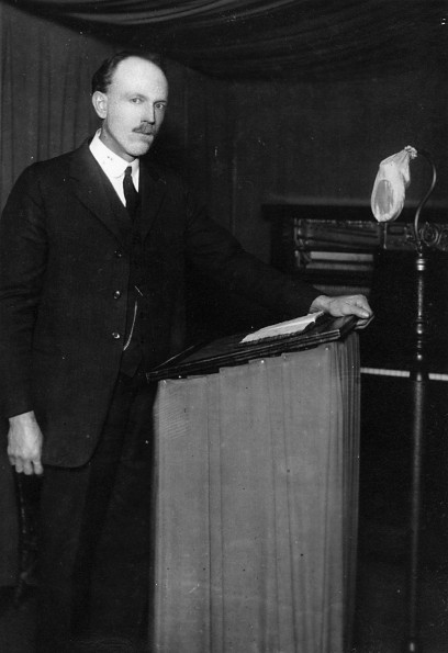 [William R. French standing at a lectern]