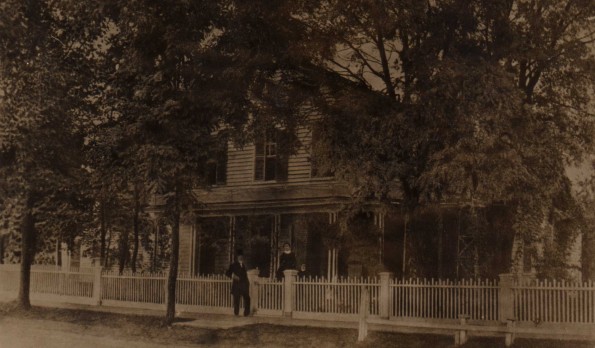 [Flavius J. and Harriet B. Littlejohn standing in front of their home in Allegan, Michigan with an unknown girl]