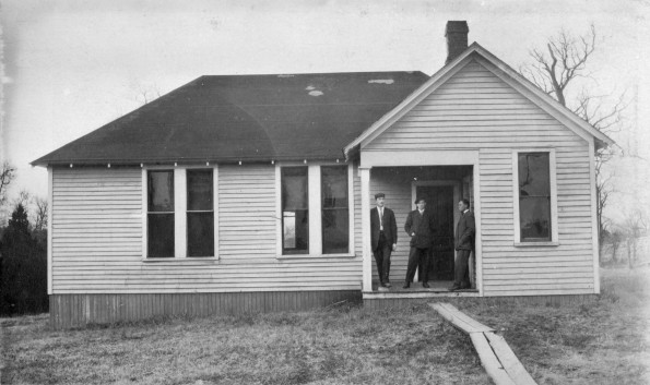 Three unknown men standing in front of an unknown building at Madison College